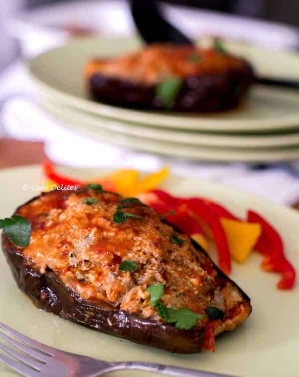 Beef Stuffed Eggplants with some slices of red and yellow bell peppers in the background on the plate