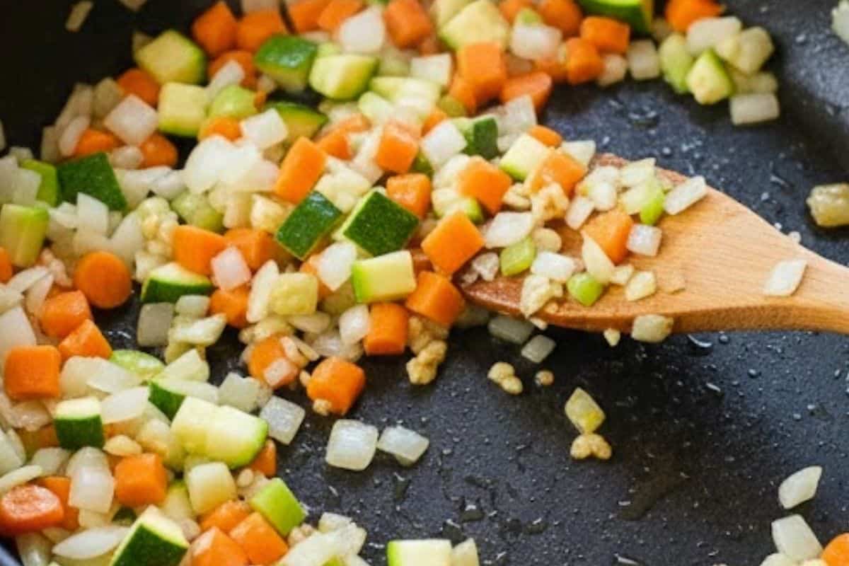 In a pan over medium heat, sauté onion, garlic, carrot, and zucchini until the onion becomes soft