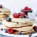 Fluffy Greek Yoghurt and Mixed Berry Choc Chip Pancakes being stack on each other with some fresh berries on top
