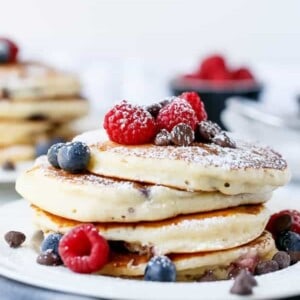 Fluffy Greek Yoghurt and Mixed Berry Choc Chip Pancakes being stack on each other with some fresh berries on top