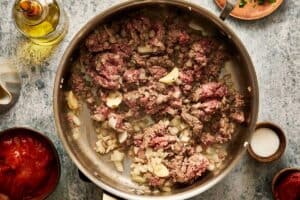 beef being cooked with onions, oil, garlic until bowned