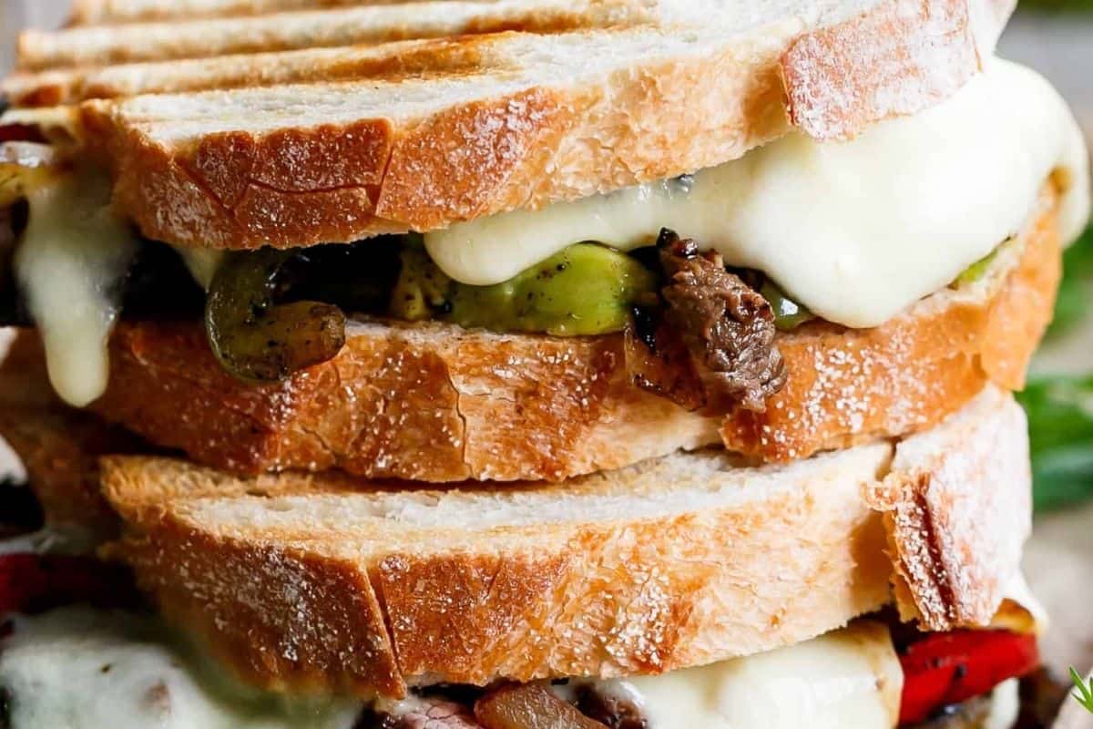 Layer the bread with peppers, onions, sliced steak, yoghurt or sour cream, avocado and mozzarella,