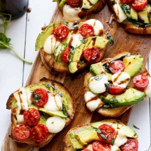5 pieces of Avocado Caprese Crostini on a wooden tray ready to enjoy