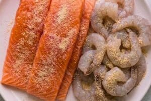 Salmon and shrimp being seasoned