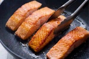 Fully cooked salmon in a pan with heat oil