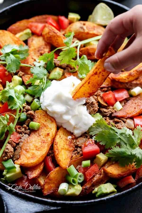 Potato wedges being dipped into thick cream sauce