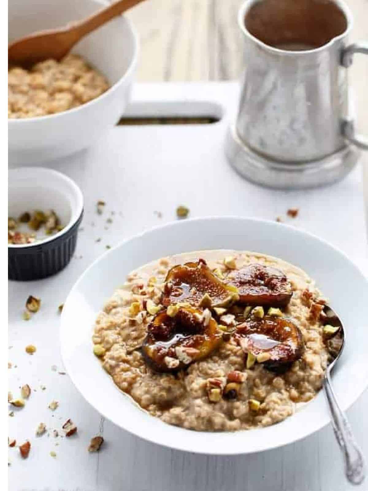 A bowl of creamy oats with caramelized figs on to halved and sprincked with crushed nuts.