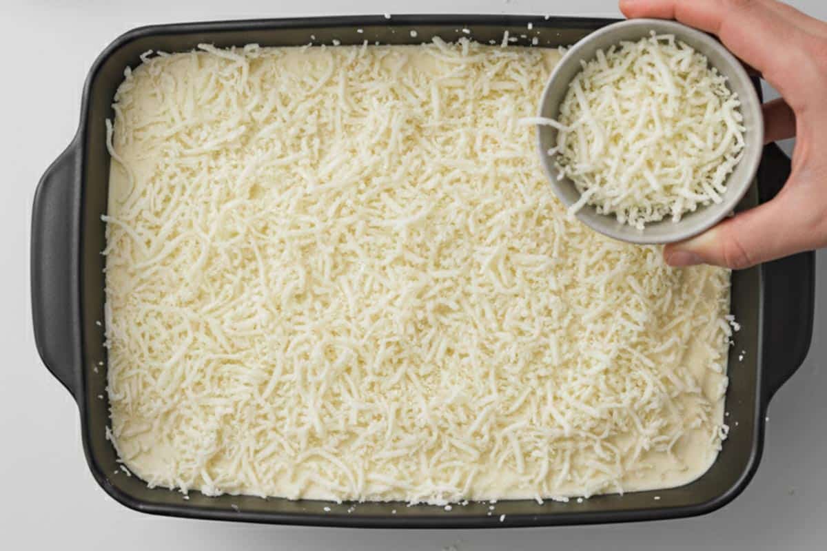 Sprinkling the mozzarella cheese over the béchamel.