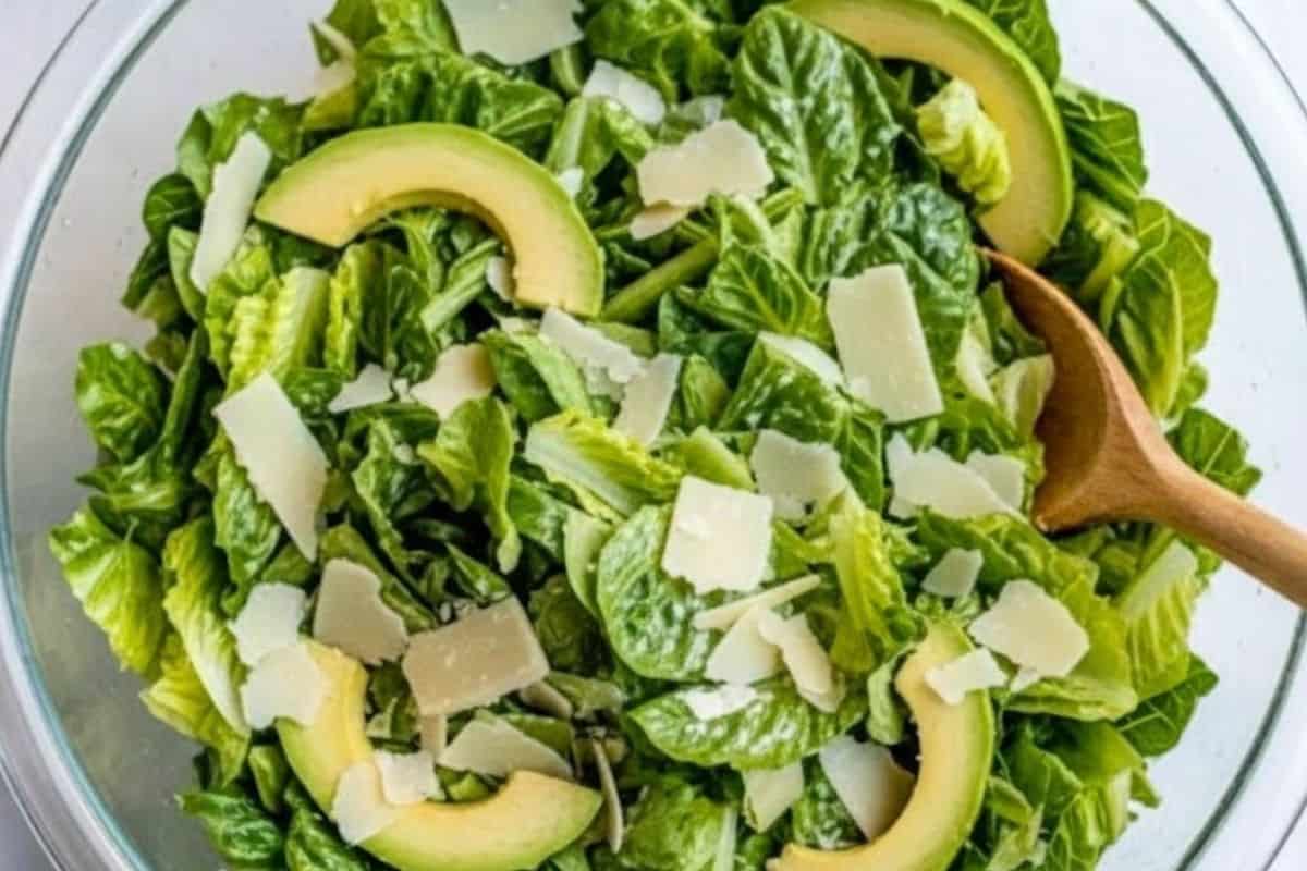 Add the washed and dried baby cos lettuce to a large serving bowl along with the avocado slices and shaved parmesan cheese.