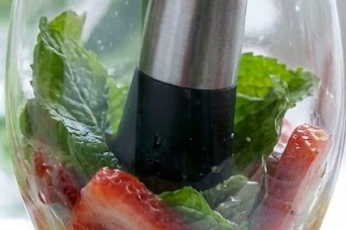 Divide mint leaves and sliced strawberries between four glasses, juice one lime and add about a teaspoon to each, then gently muddle