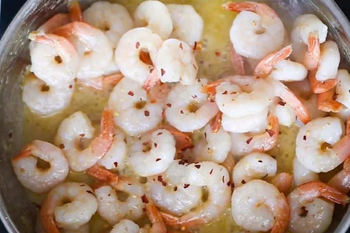 Seasoning the shrimp with salt, pepper, and red pepper flakes.