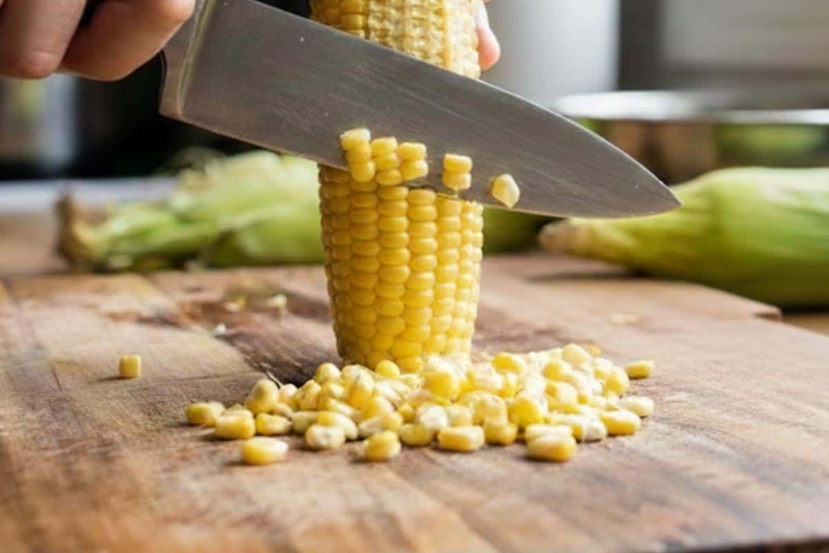 Removing the kernels of the corn using a knife.