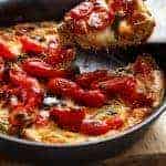 Garlic infused, Caprese Frittata with pan fried, juicy tomato and fresh basil flavors in a pan.