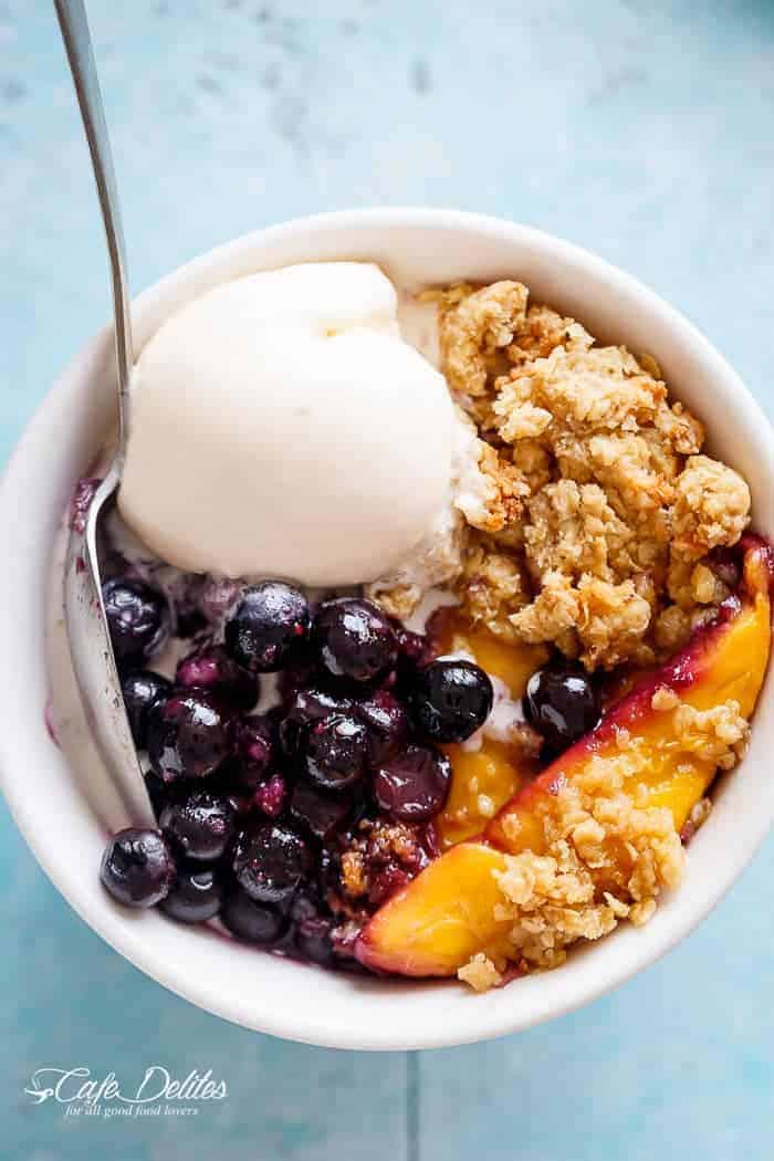 Mango Blueberry Crumble with fresh berries and ice cream scoops in a bowl