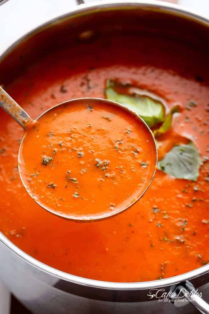 A spoon filled with Creamy Roasted Tomato Basil Soup