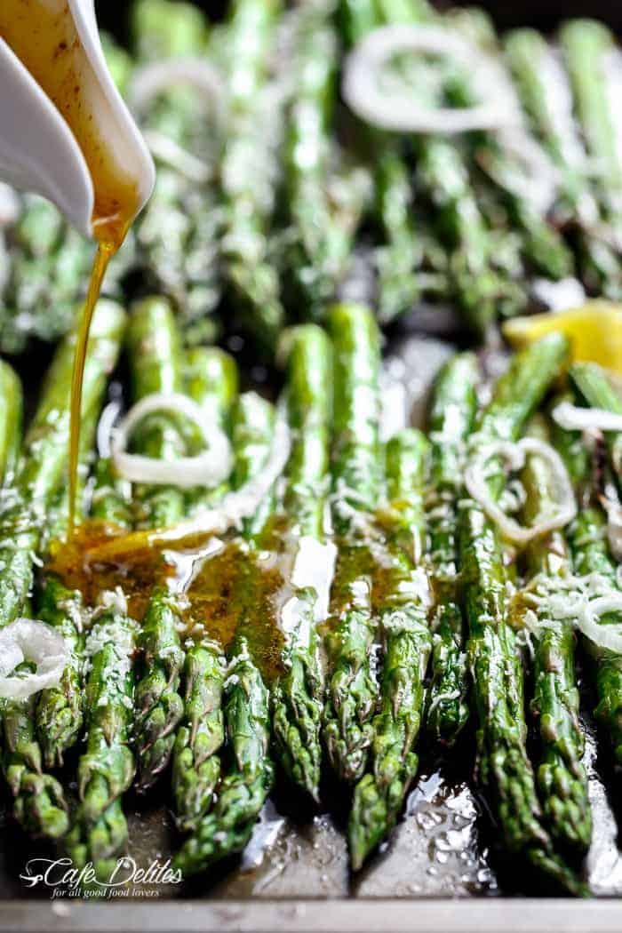 A dressing pouring over Garlic Browned Butter Baked Asparagus with Parmesan Cheese