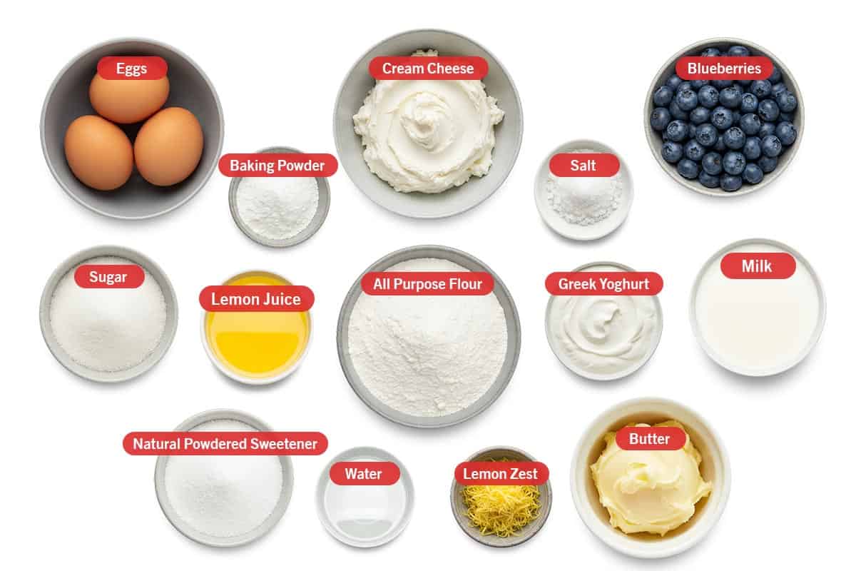 Top shot of ingredients: eggs, baking powder, cream cheese, salt, blueberries, sugar, lemon juice, all purpose flour, greek yogurt, milk, natural powdered sweetener, water, lemon zest, and butter.
