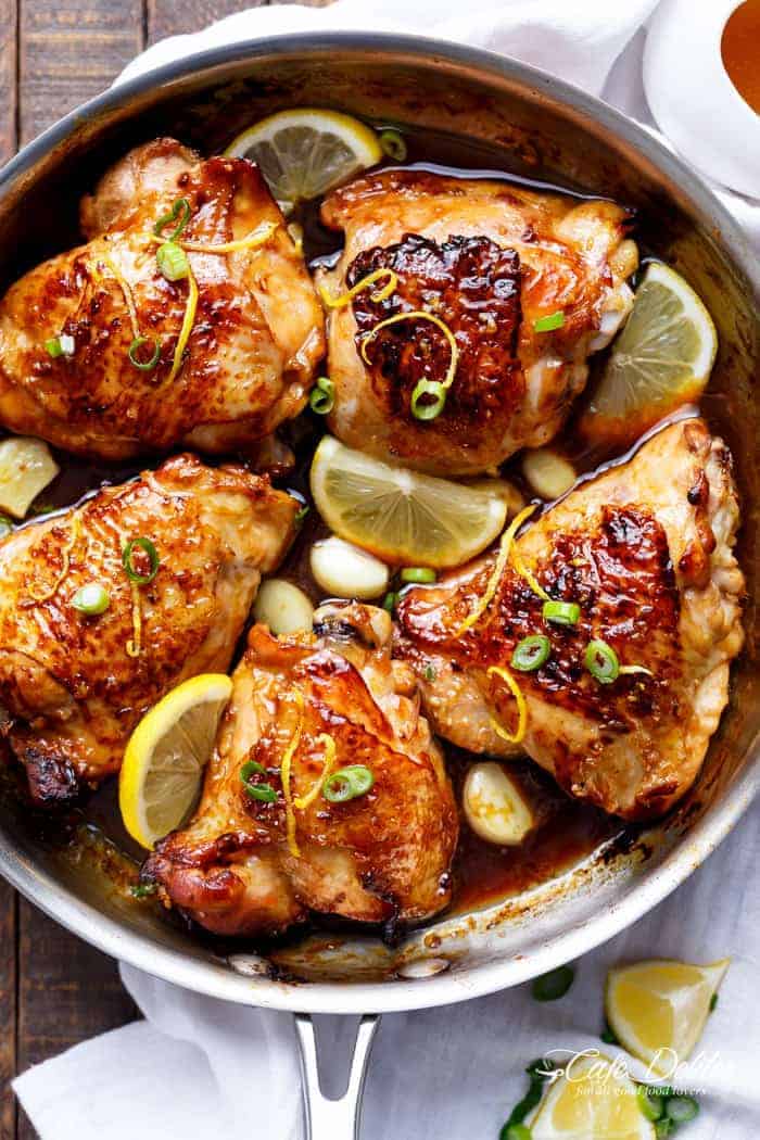 Honey Lemon Garlic Chicken pieces with lemon wedges in a pan