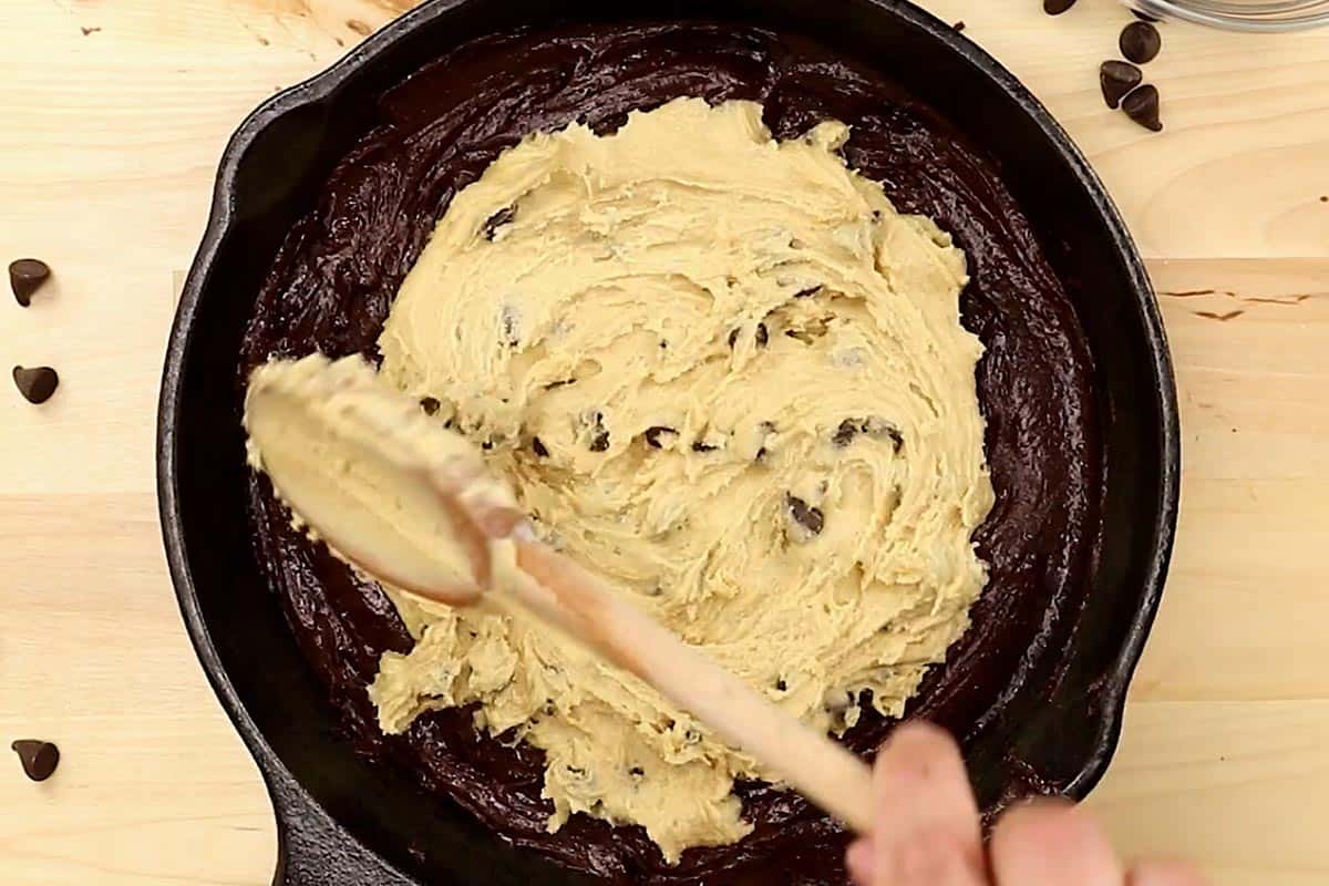 Spreading the brownie batter evenly into the prepared skillet.