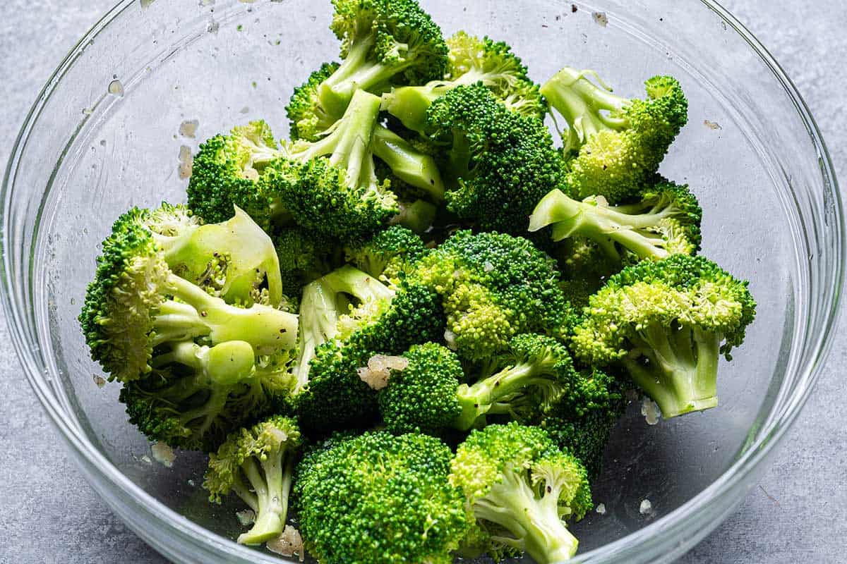 Broccoli in a clear bowl against a grey background