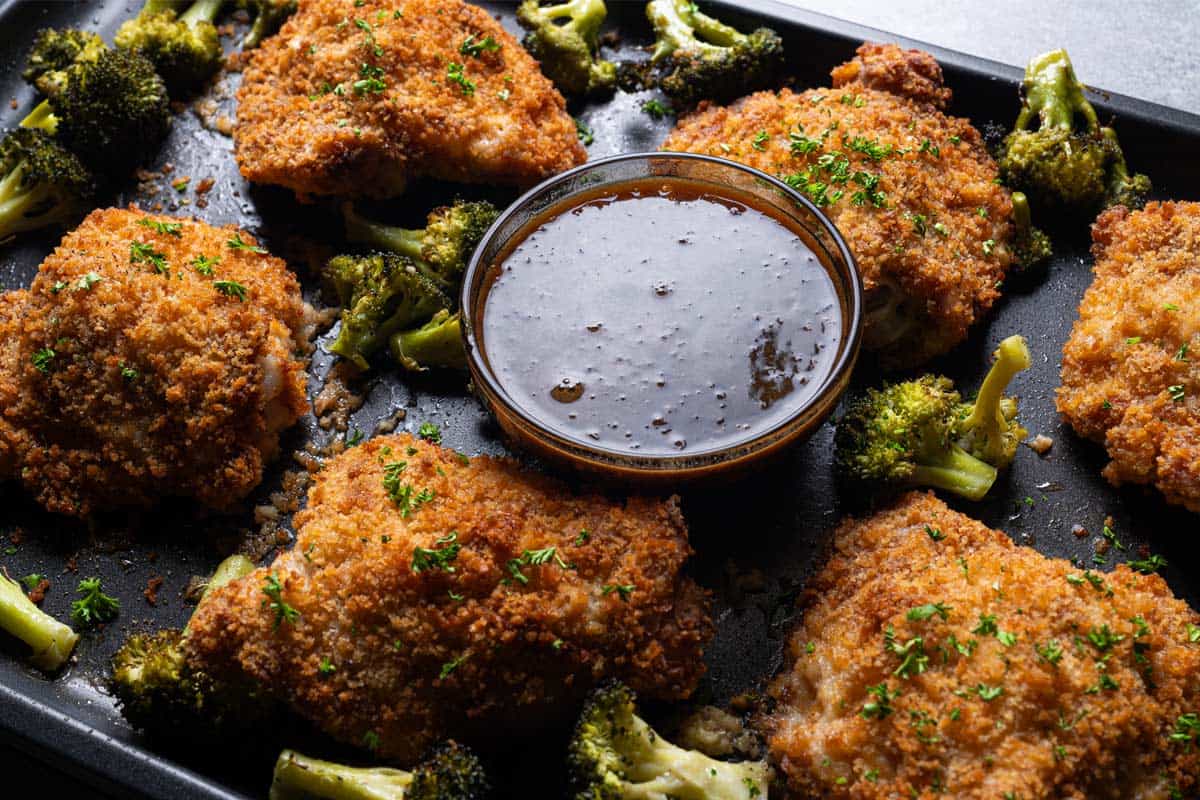 Oven Fried Chicken with broccoli and honey garlic dipping sauce cooked on a tray