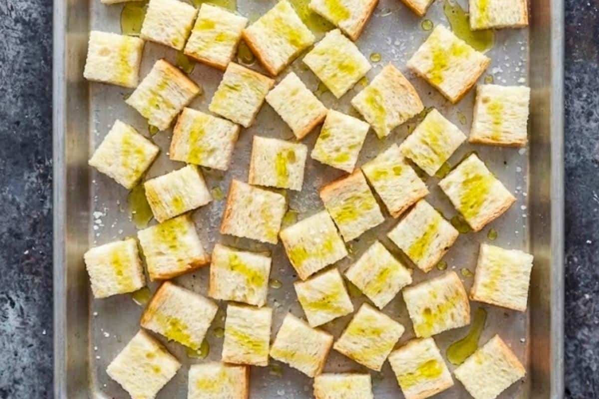 Spread cubed bread on a baking tray, drizzle or spray with olive oil, and grill on the middle rack until golden and crisp.