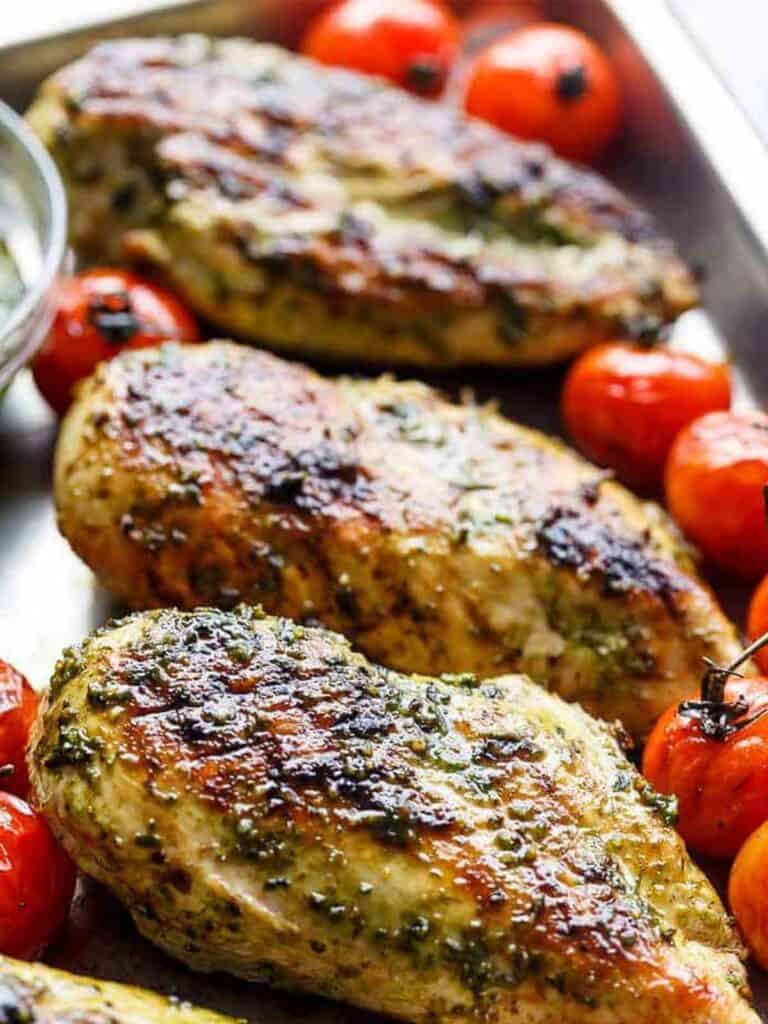 image focusing on Grilled chicken pieces with roasted tomatoes on the sides