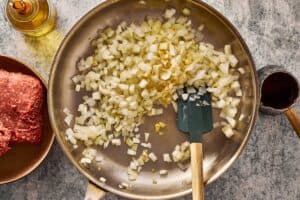 Diced onion and garlic cooking in a skillet until softened