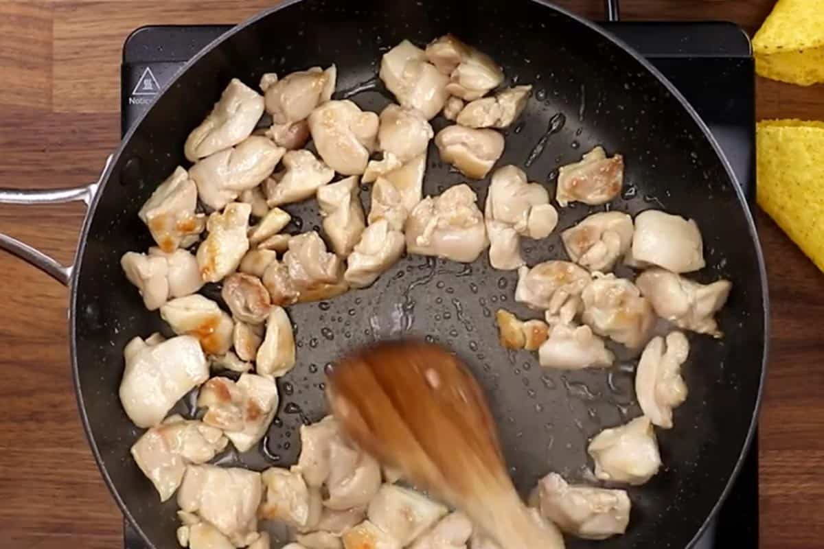 Searing the diced chicken in a skillet.