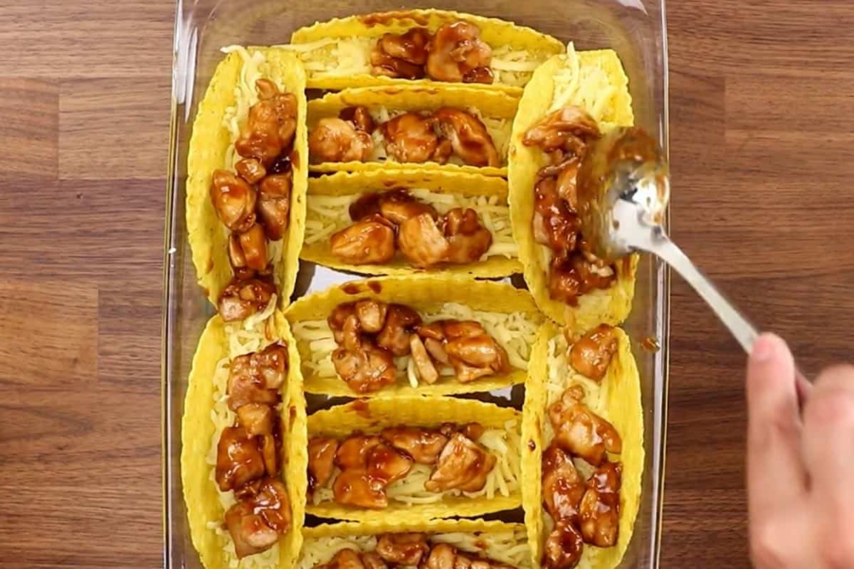 Filling the taco shells with chicken mixture.