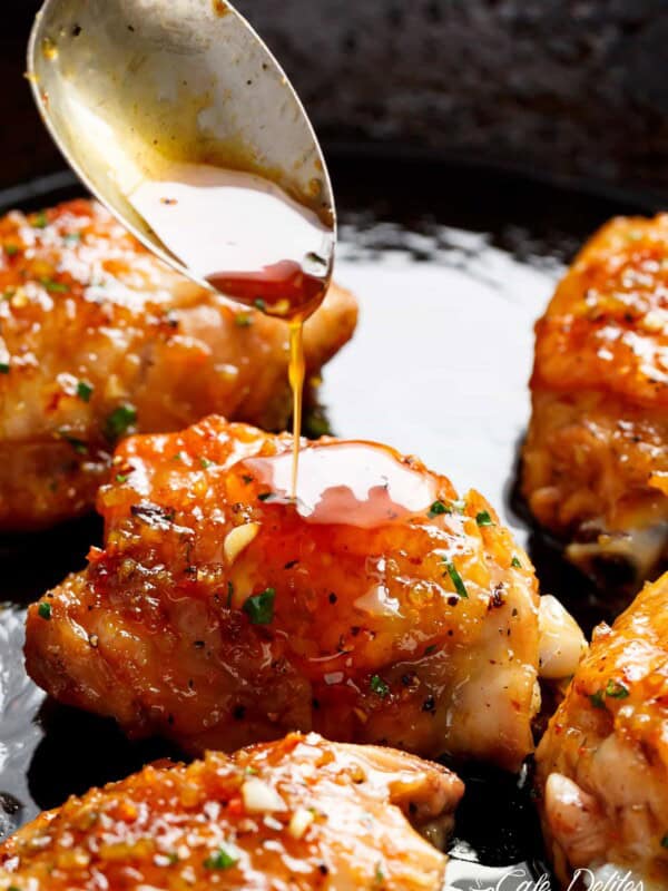 Honey dripping over the Garlic Chicken pieces in a pan