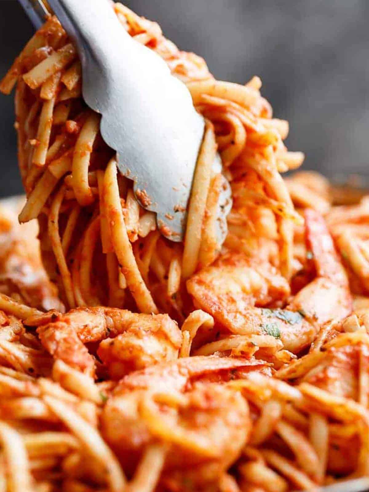 tongs holding up 15-Minute Creamy Tomato Garlic Butter Shrimp