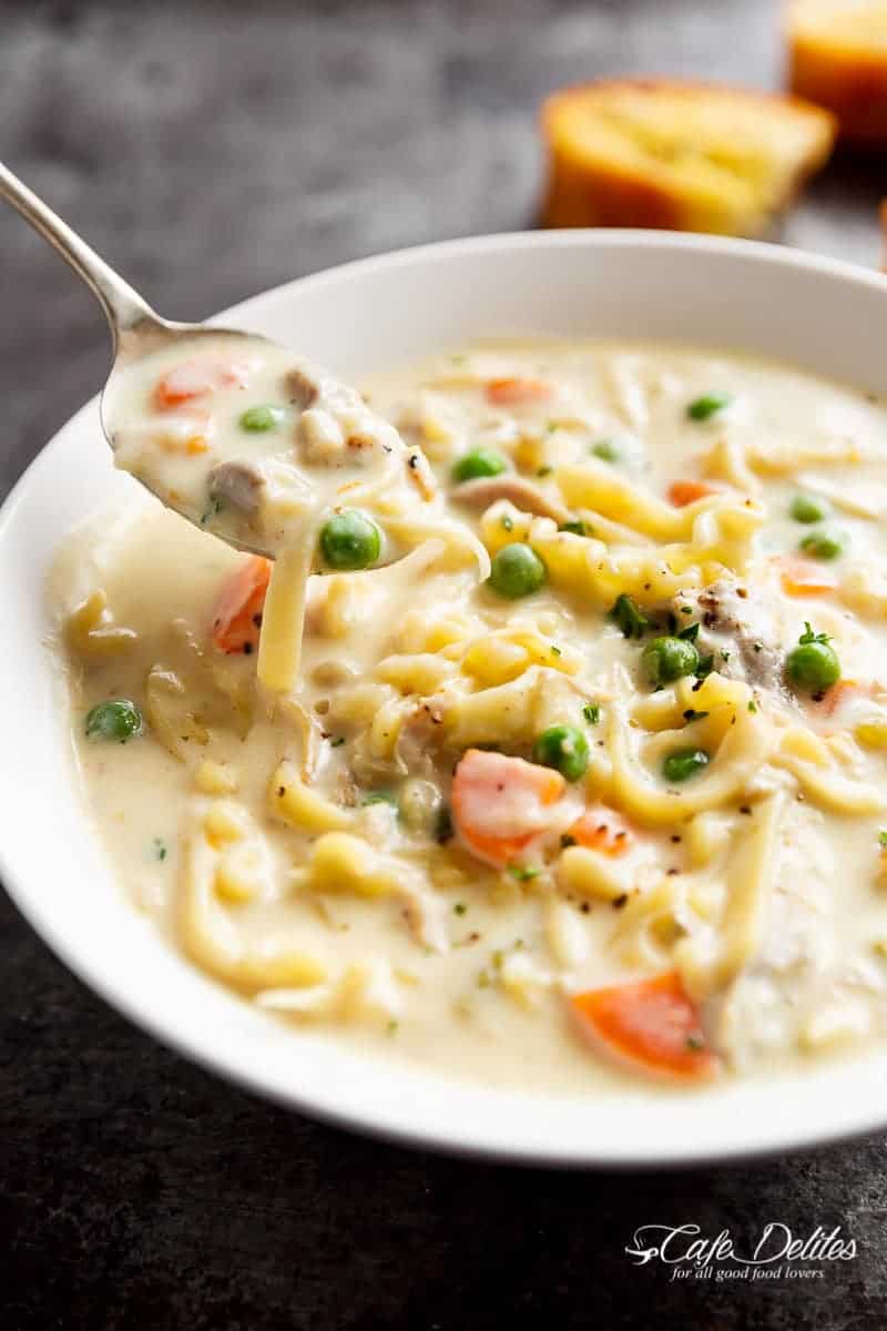 A spoon carrying a Creamy Chicken Noodle Soup from the bowl