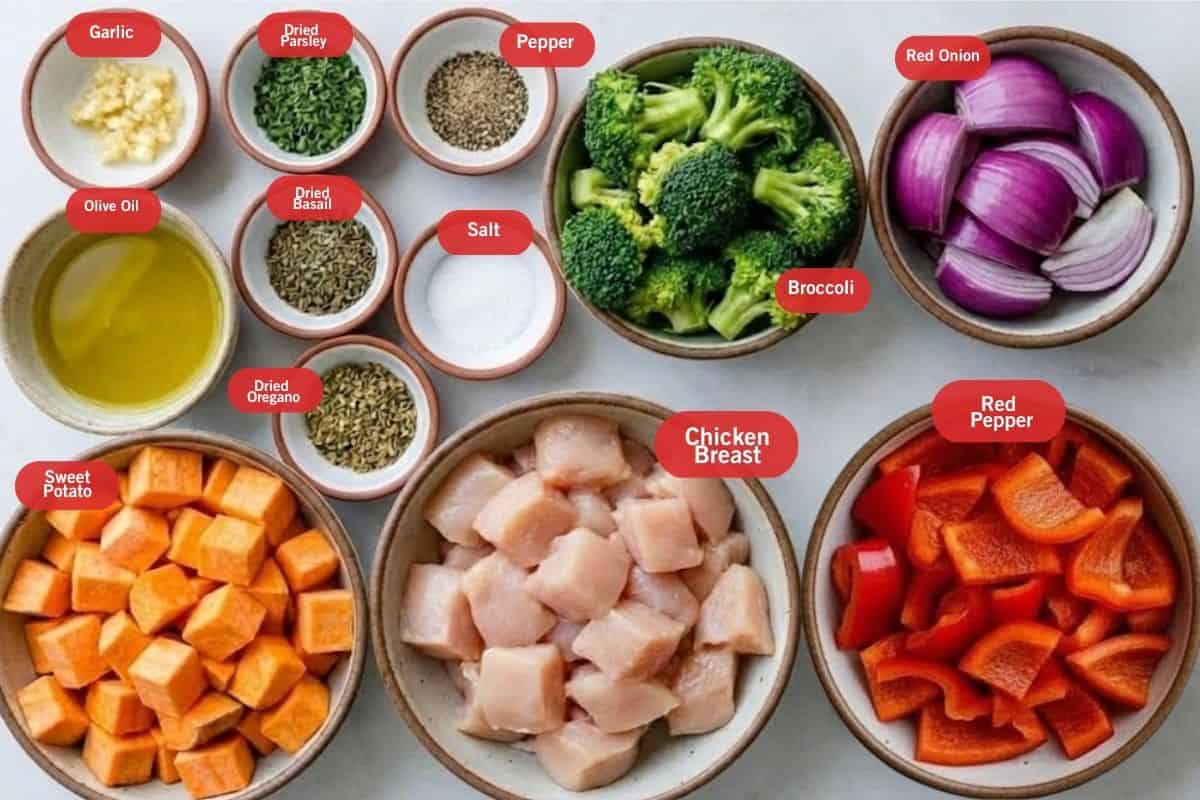 Flat lay photo of ingredient shot of garlic, dried parsley, pepper, dried basil, broccoli, red onion, red pepper, chicken breast, dried oregano, salt, sweet potatoes, olive oil, pepper