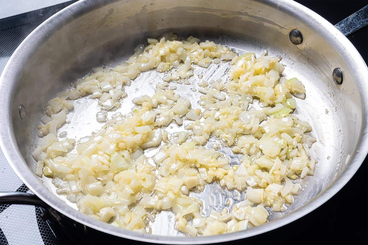 butter and onion and garlic in a skillet being sauted