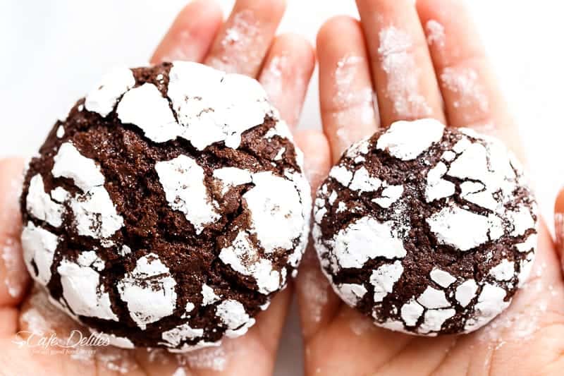 Holding Fudgy Chocolate Crinkle Cookies in each hand one cookie is bigger than the other.