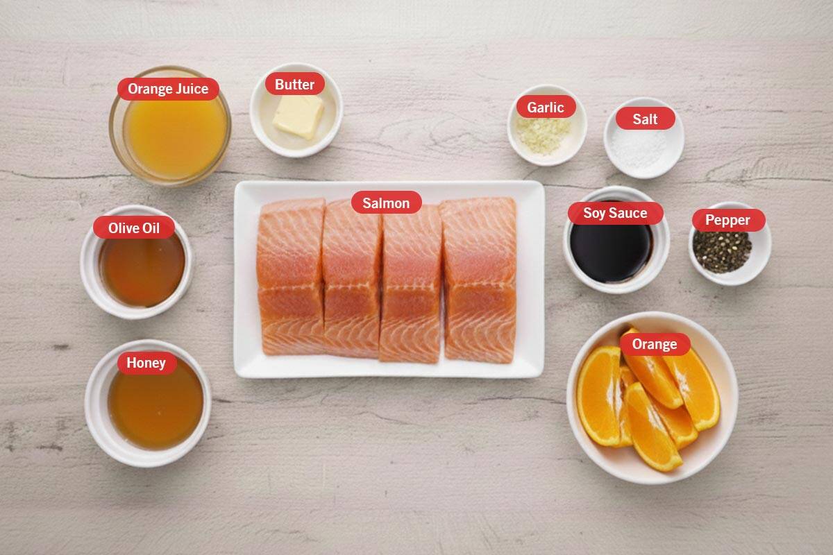 Top shot of ingredients: orange juice, butter, garlic, salt, soy sauce, pepper, orange, salmon, honey, and olive oil.