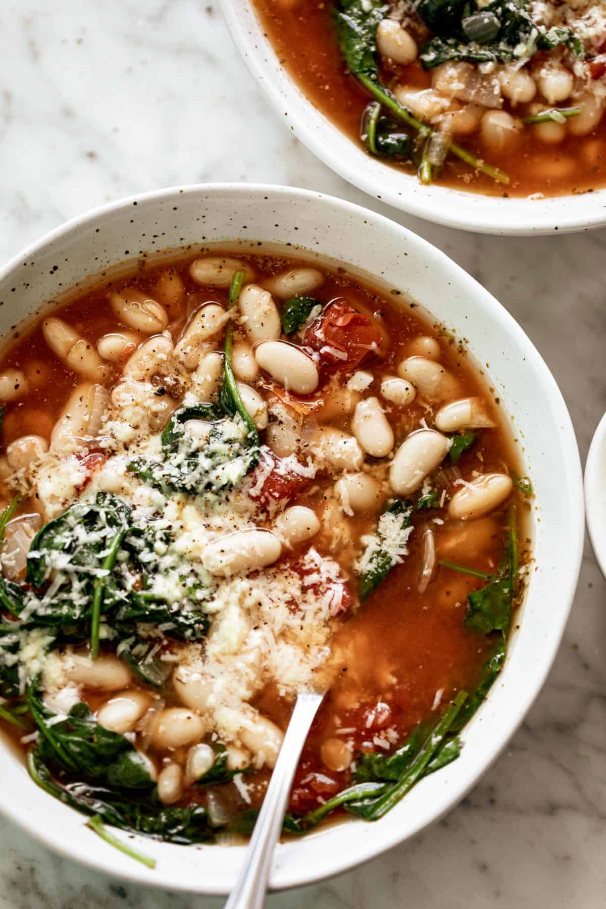 A bowl of White Bean Parmesan Spinach Soup | https://cafedelites.com White Bean Parmesan Spinach Soup ready in 10 minutes is may kind of soup! Make a double batch and have plenty of leftovers for the weekly dinner rush!