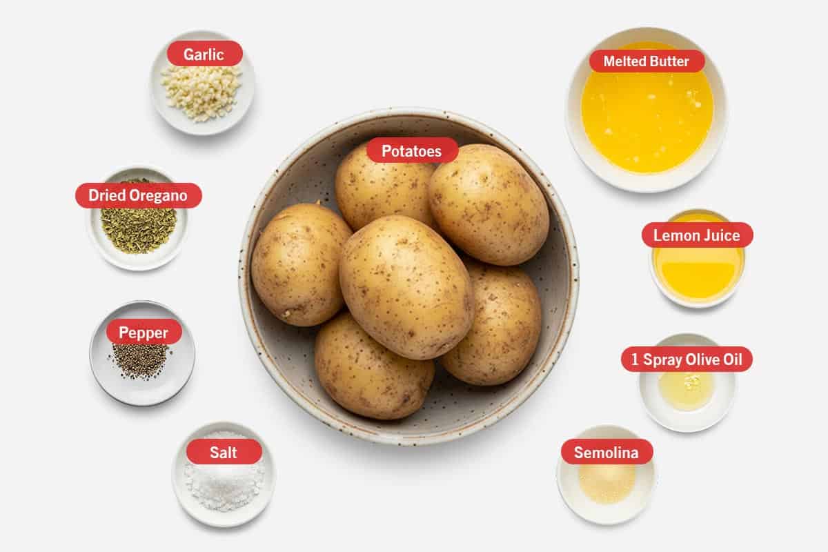 Top shot of ingredients: garlic, dried oregano, pepper, salt, potatoes, melted butter, lemon juice, 1 spray of olive oil, and semonila.