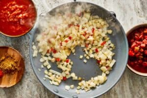 a top down view of a pan with diced up vegetables being fried in the pan