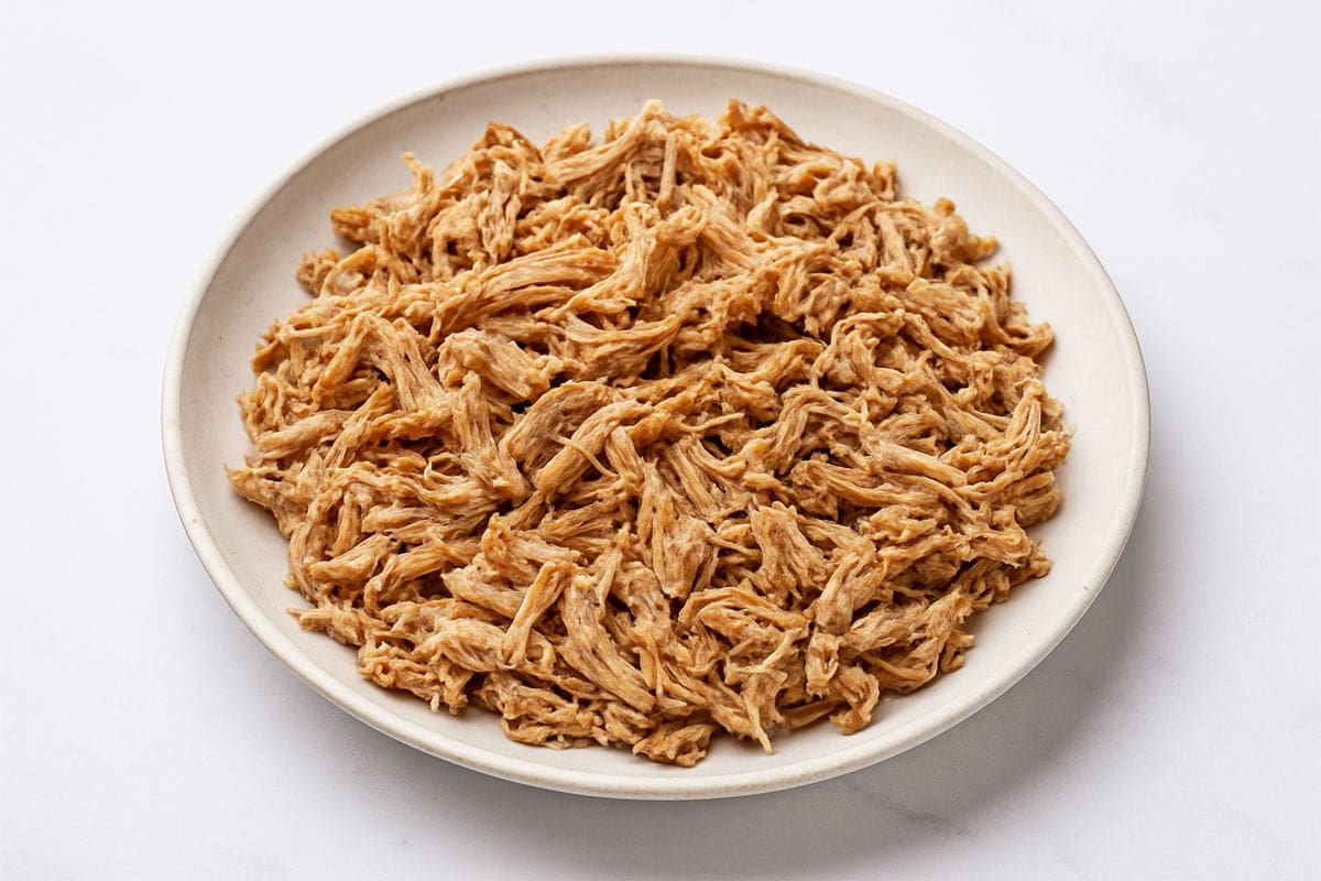 Shredded pork served in a white bowl after being slow-cooked until tender and juicy.