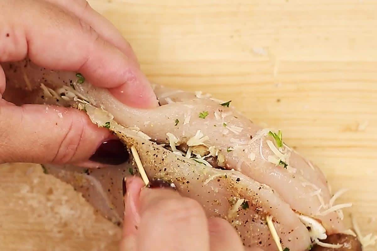 Securing the chicken with toothpicks.