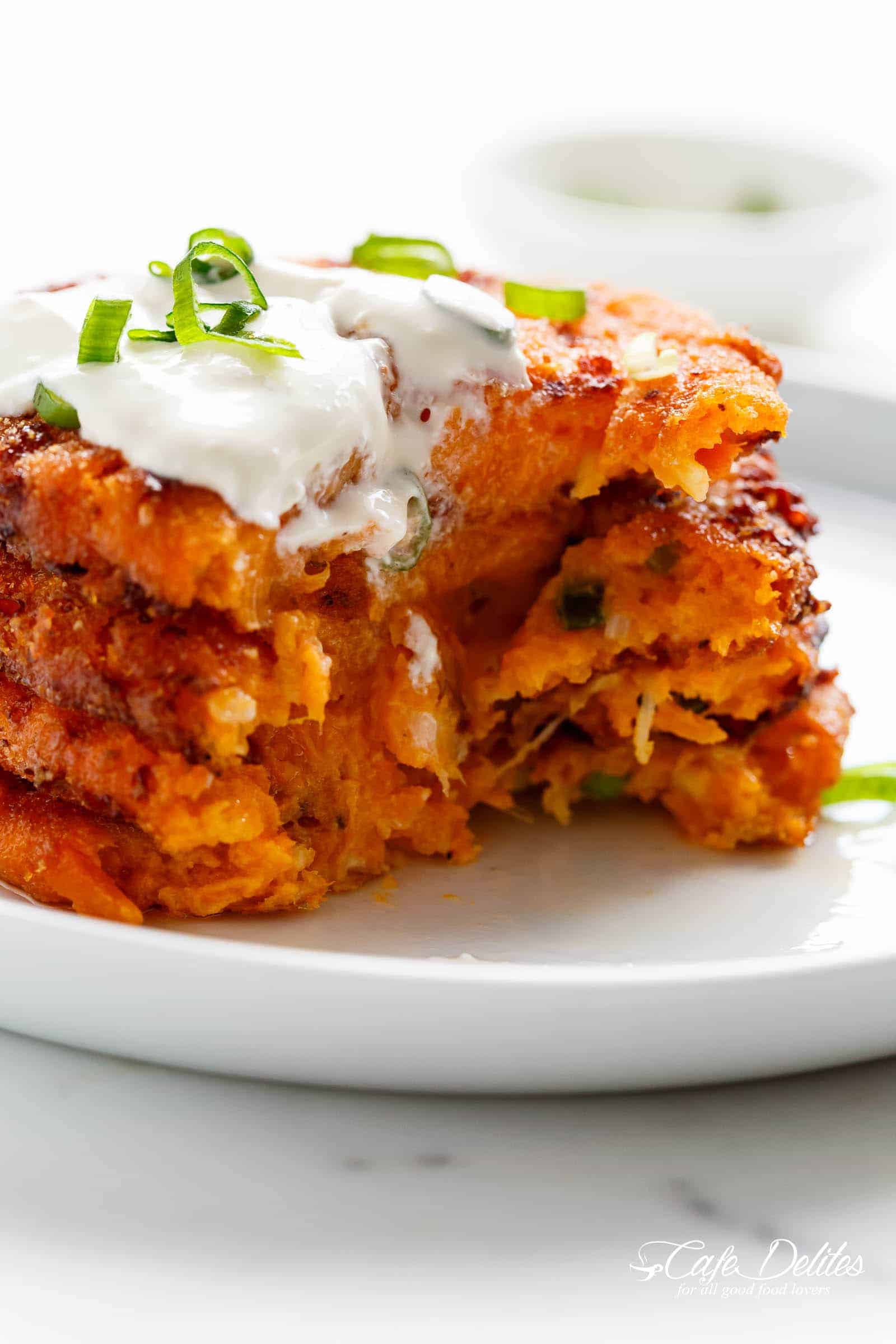 A bite taken from Cheesy Mashed Sweet Potato Cakes are Cheesy on the inside, so crispy on the outside, and so easy to make!