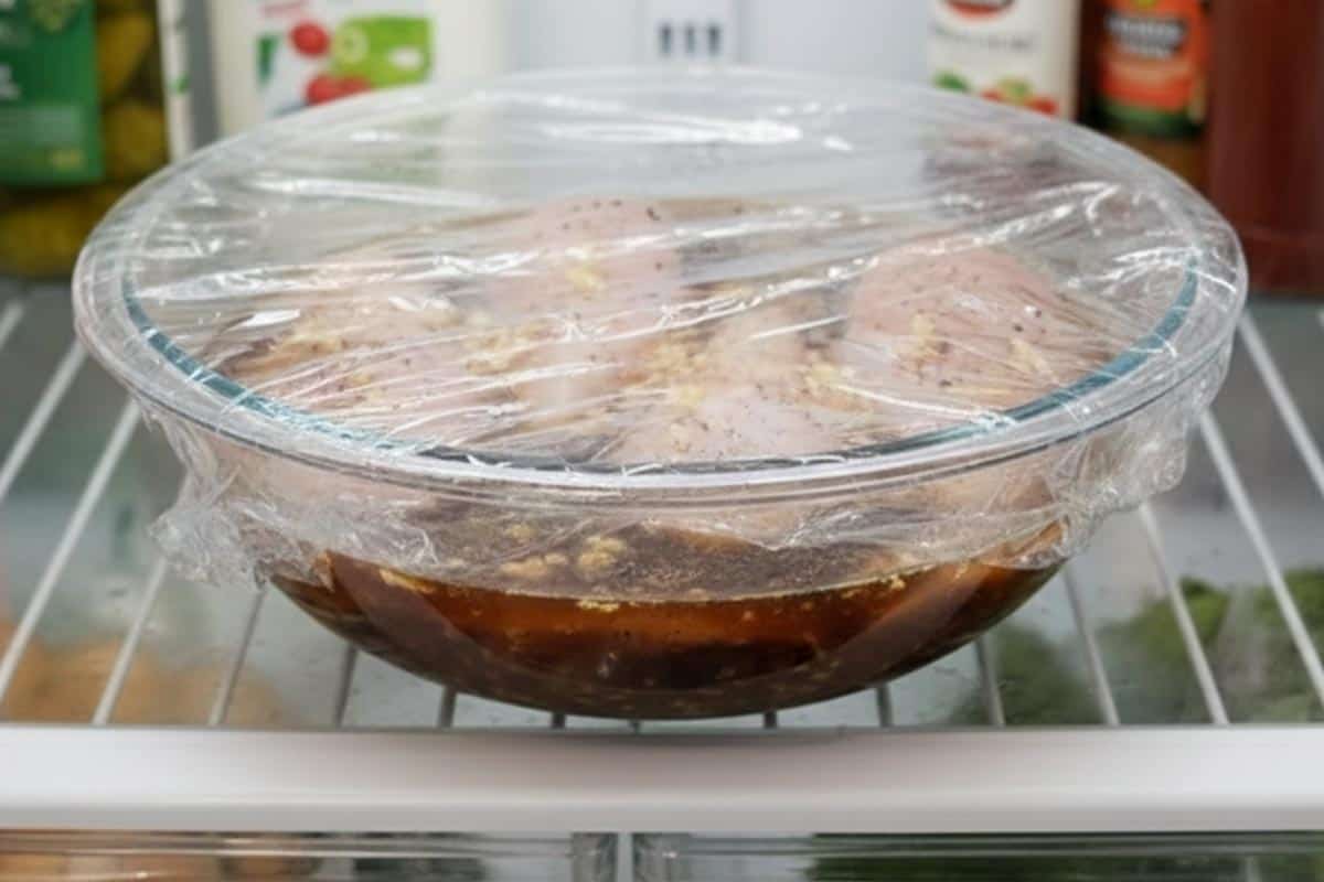 Marinating the chicken with lager, garlic, salt, and pepper in a bowl.