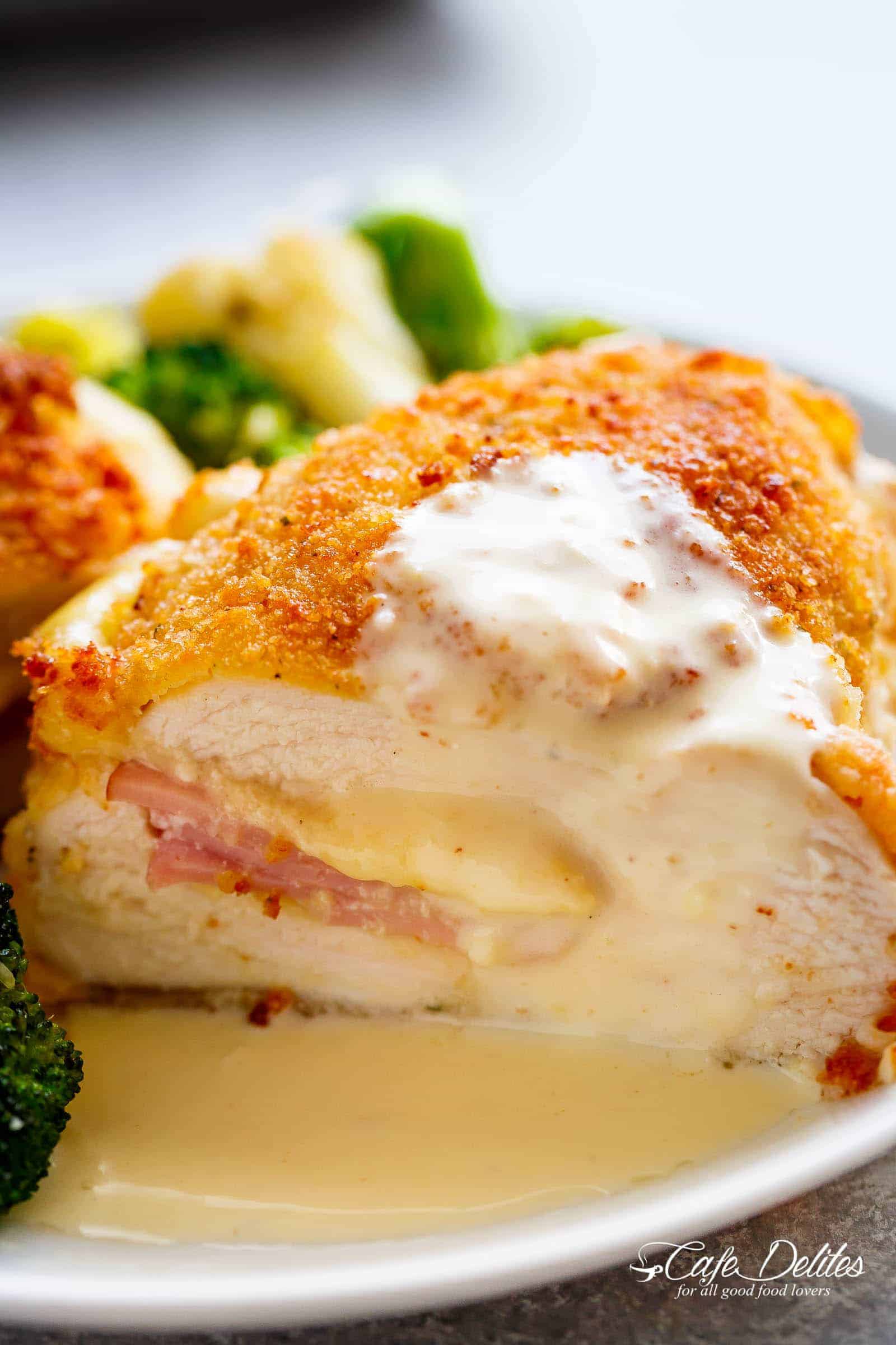 Side view of Crispy crumbed chicken breasts filled with Dijon mustard, Swiss cheese and ham, baked with vegetables and served with an incredible Dijon Cream Sauce