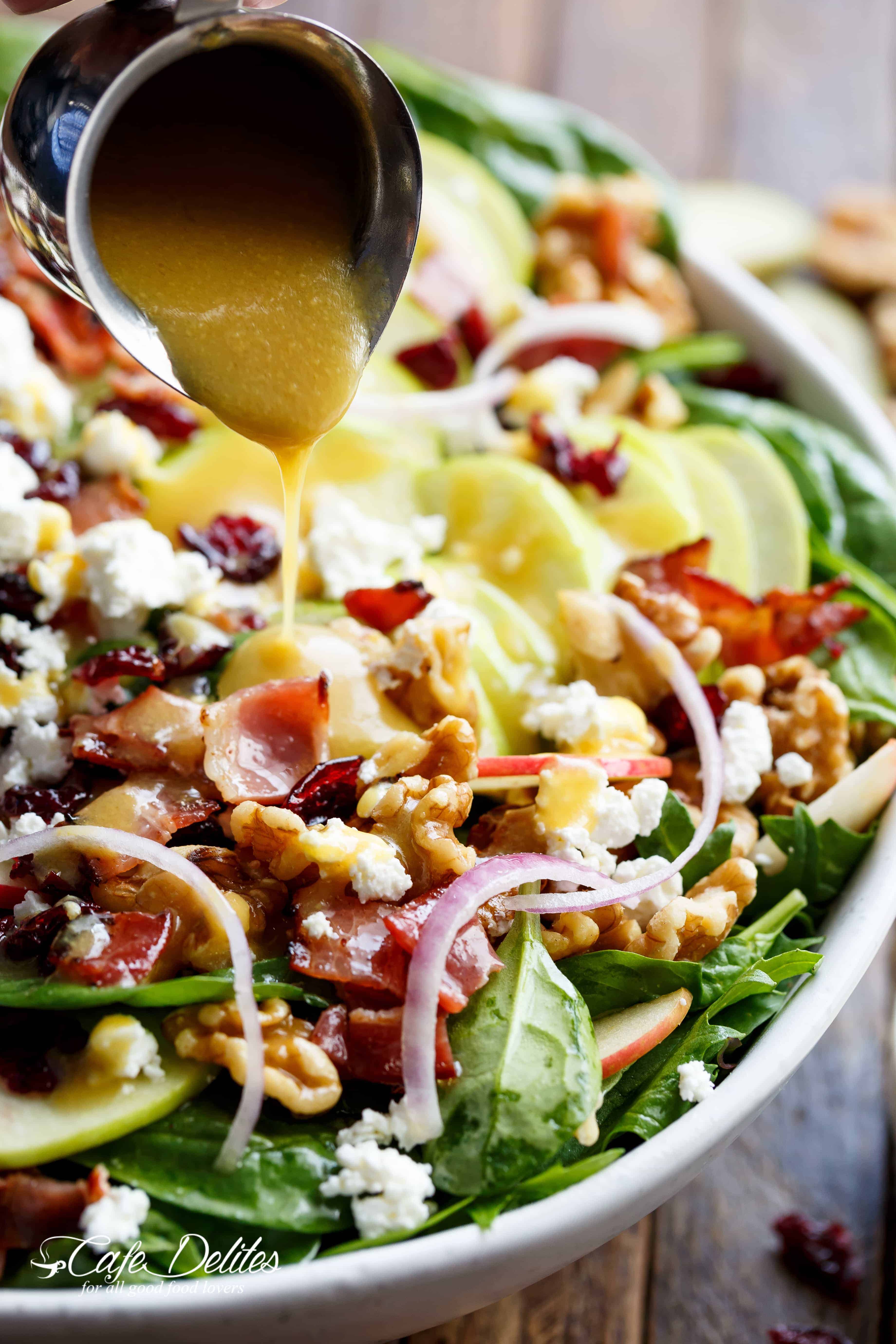 Honey dressing pouring on Honey Dijon Apple Bacon Cranberry Salad