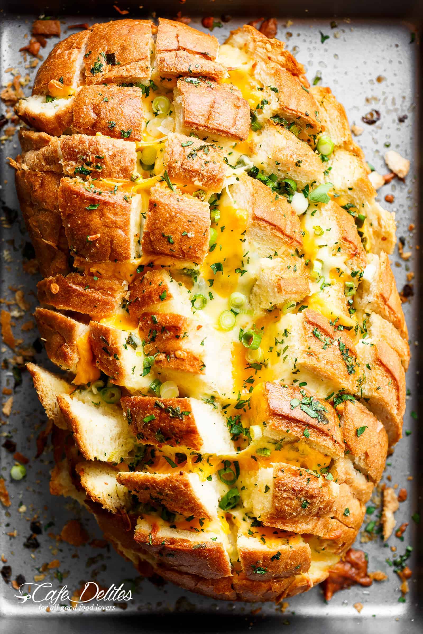 Top view image of Bloomin\' Onion Garlic Bread is ultra cheesy with two types of cheese, garlic butter and green onions baked between wedges of fresh bread! 