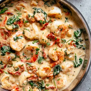 Creamy Garlic Butter Tuscan Shrimp coated in a light and creamy sauce filled with garlic, sun dried tomatoes and spinach in a pan