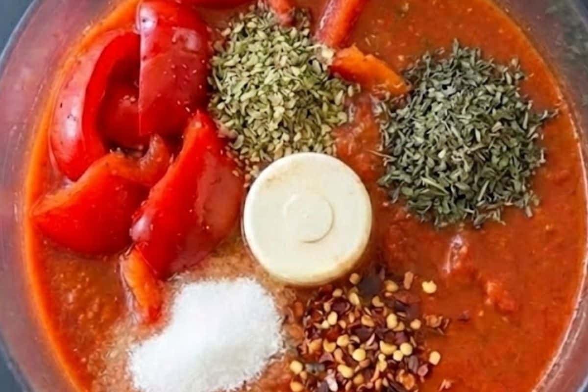 Add half of the red bell peppers, tomato sauce, oregano, basil, sugar, and red pepper flakes to a food processor then blend.