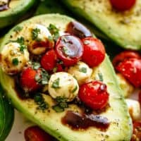 Basil Pesto Caprese Stuffed Avocado drizzled with balsamic glaze make an incredible light lunch or snack! Take creamy avocados to a different level! Sweet and juicy grape/cherry tomatoes with fresh mozzarella balls are tossed through basil pesto and spooned into avocado halves!